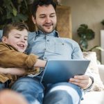 man en zoon in zetel met tablet