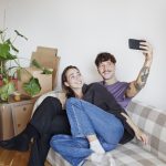 Jong koppel zit tussen de verhuisdozen en neemt selfie