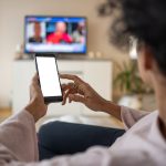Vrouw kijkt naar tv via app op smartphone