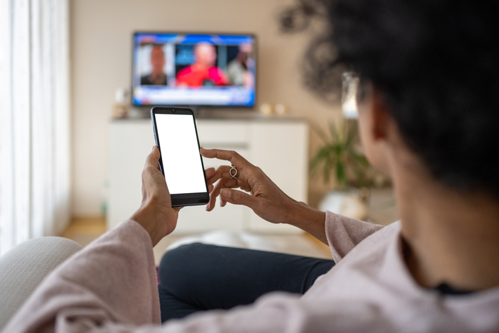 Vrouw kijkt naar tv via app op smartphone