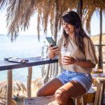 Vrouw kijkt op haar telefoon in een strandbar