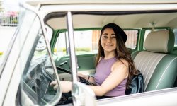 Vrouw rijdt rond in groene oldtimer.
