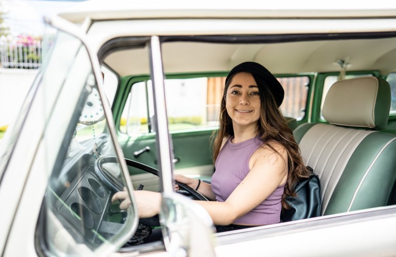 Vrouw rijdt rond in groene oldtimer.