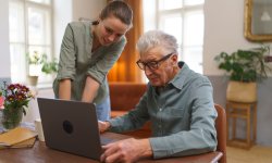 Oudere man sluit online een uitvaartverzekering af met behulp van zijn kleindochter.